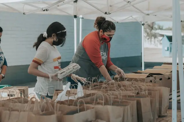 Volunteers packing food bags at an outdoor community distribution event